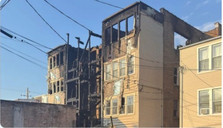 Exterior view of a heavily charred multi-story apartment building showing fire damage after the house fire.